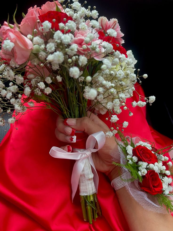 a woman in a red dress holding a bouquet of roses and baby's breath