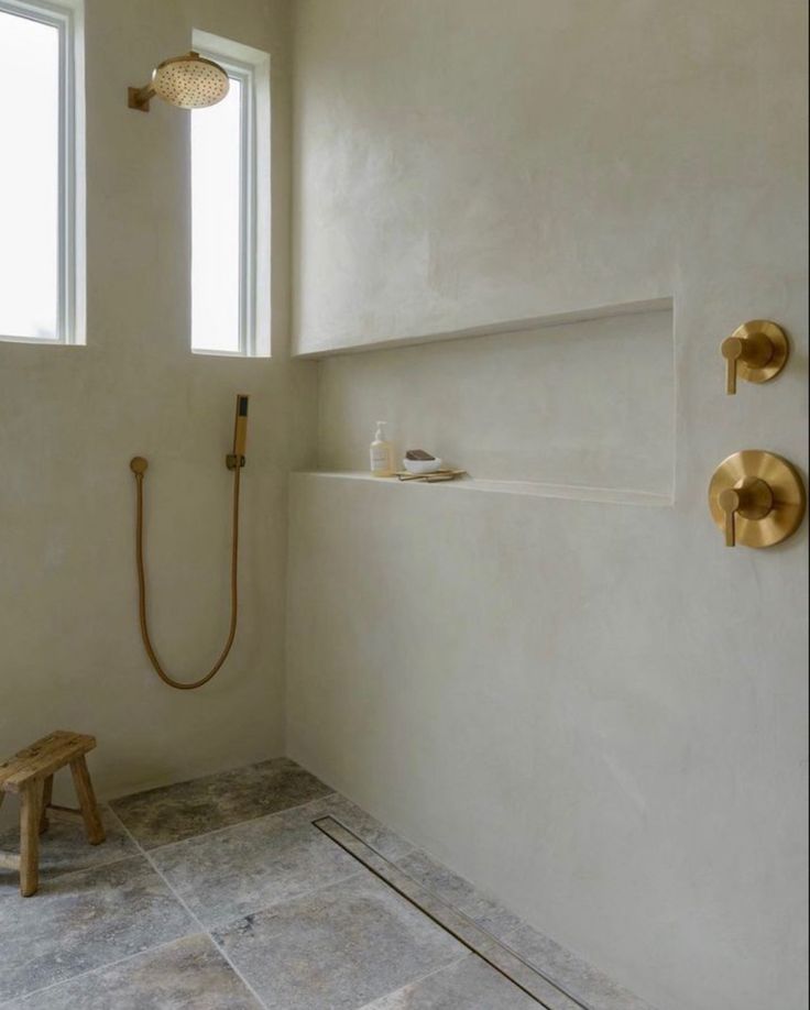 a white bathroom with gold fixtures on the shower head and hand held faucet