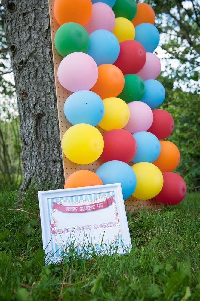 a bunch of balloons that are in the grass near a sign with a card on it