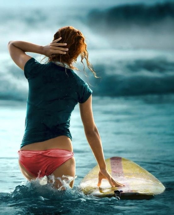 a woman is standing in the water with her surfboard