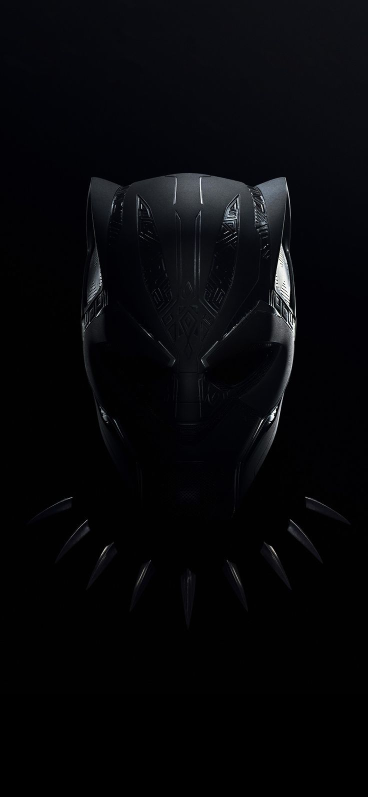 a black mask with spikes on it's face is shown in the middle of a dark background