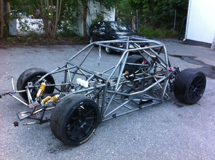 a car that is sitting on the ground in front of some trees and cars behind it