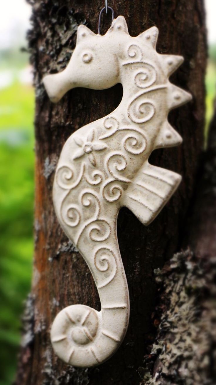 a ceramic seahorse hanging on a tree