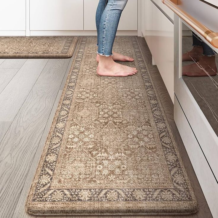 a woman standing on top of a rug in a kitchen next to an oven and cabinets