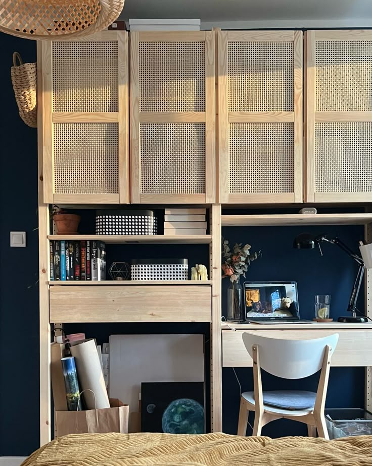 a bedroom with a bed, desk and bookshelf next to it in front of a blue wall