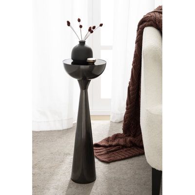 a black vase sitting on top of a table next to a white chair in a living room