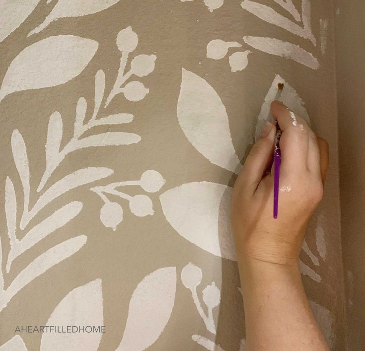 a person is painting a wall with white paint and purple pencils on the wall