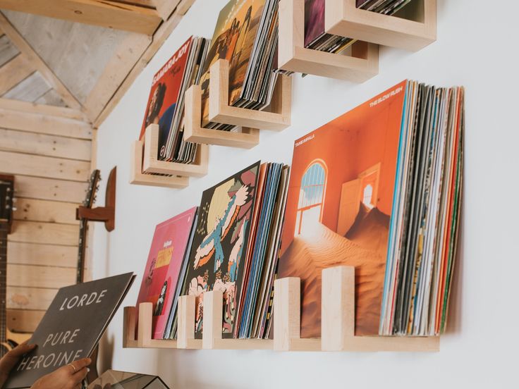 a man is reading a book in front of a wall full of record albums and cds