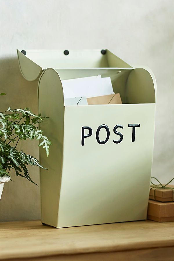 a mailbox sitting on top of a wooden table next to a potted plant