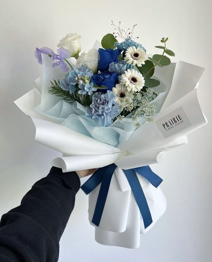 a person holding a bouquet of blue and white flowers