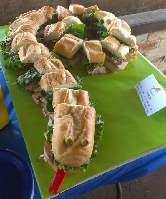 two sandwiches are on a green tray with toothpicks in them and one has been cut into smaller pieces