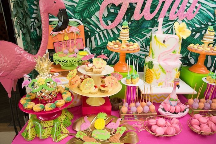 a table topped with lots of desserts next to a flamingo sign