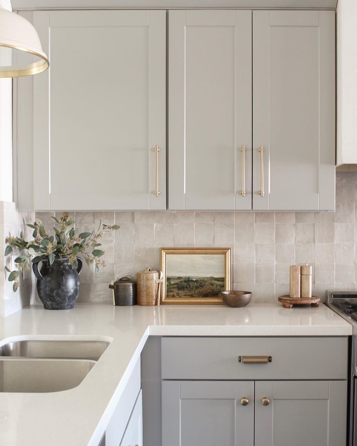 a kitchen with gray cabinets and white counter tops, gold trim on the cabinet doors