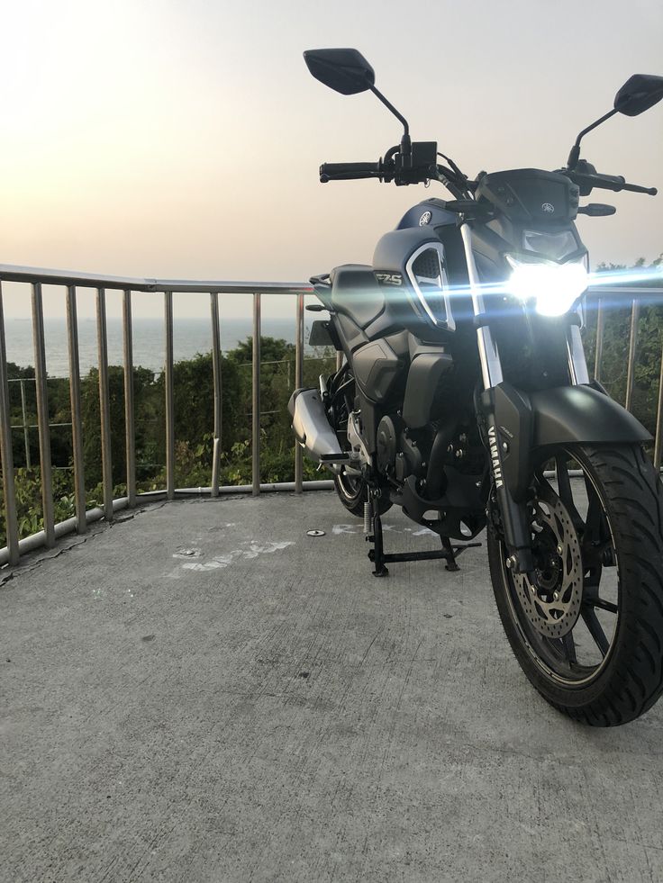 a motorcycle parked on top of a parking lot next to a metal fence and railing