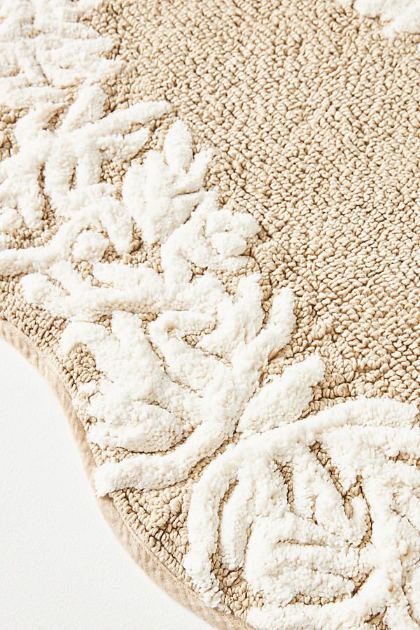 a white rug with an intricate design on the top and bottom corner is shown in close up