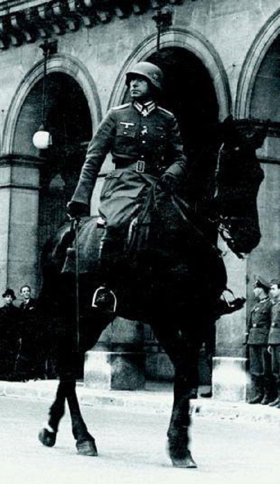 an old black and white photo of a man in uniform on a horse with people standing around