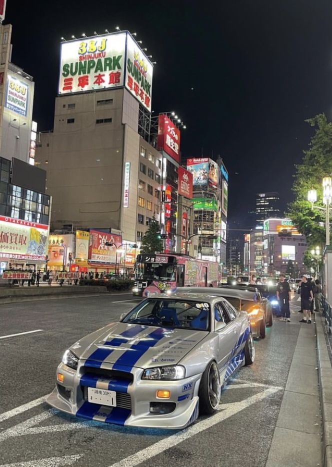 a car parked on the side of a road in front of tall buildings at night