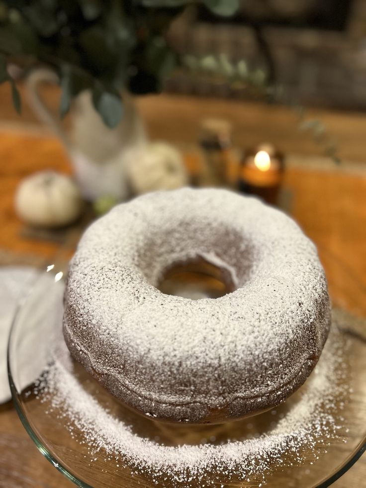 a frosted donut sitting on top of a glass plate next to a vase