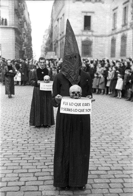 an old black and white photo shows people holding signs in front of them, with skulls on their heads