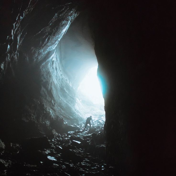 a man standing in the entrance to a dark cave