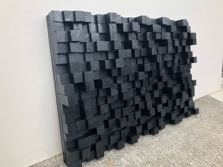 a large black piece of art sitting on top of a cement floor next to a wall