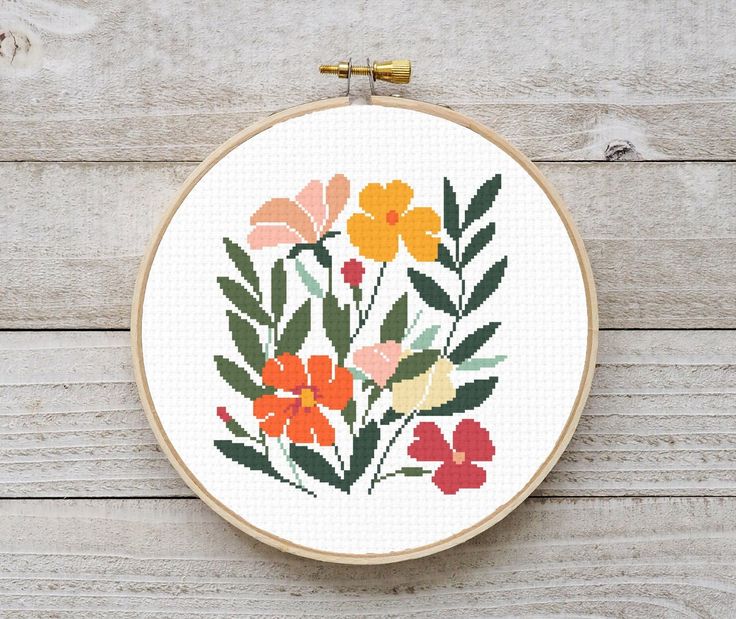 a cross stitch pattern with flowers in it on a wooden table next to scissors and thread