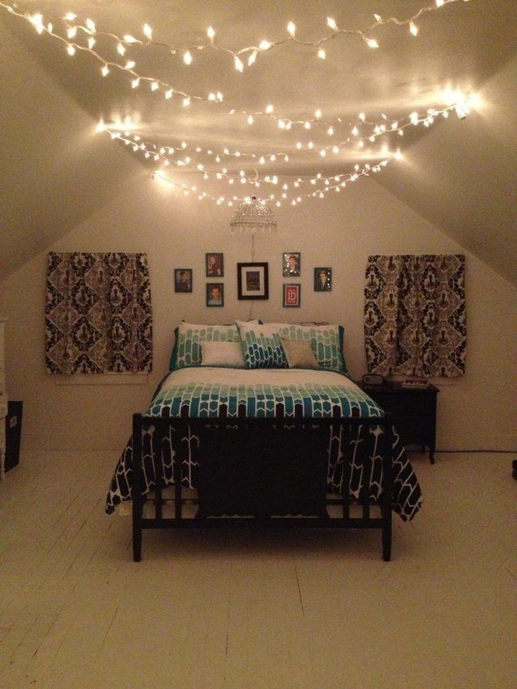 a bedroom with lights strung from the ceiling and pictures on the wall above the bed