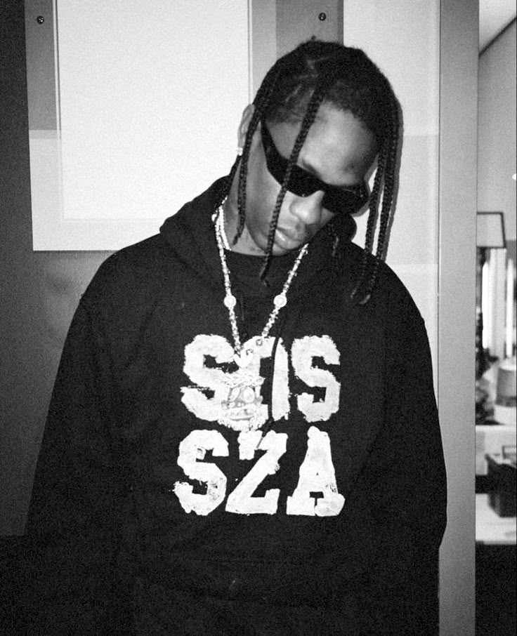 a man with dreadlocks wearing a black hoodie and sunglasses standing in a kitchen