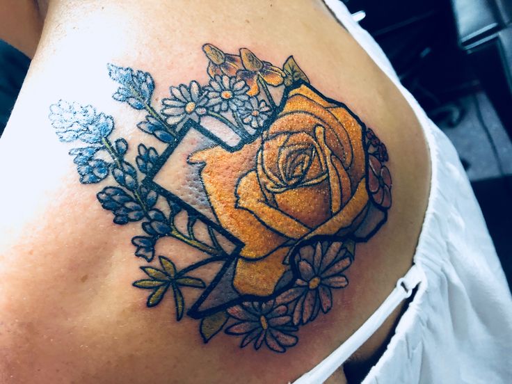 a woman's stomach with an orange rose and flowers tattoo on her left side