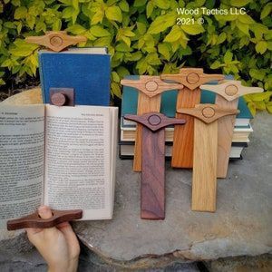 a person is holding an open book with wooden crosses on it next to some books