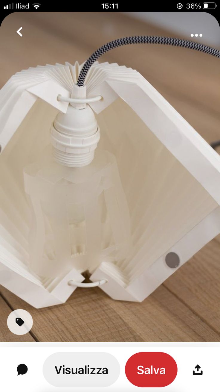 a white light fixture sitting on top of a wooden table next to a black cord