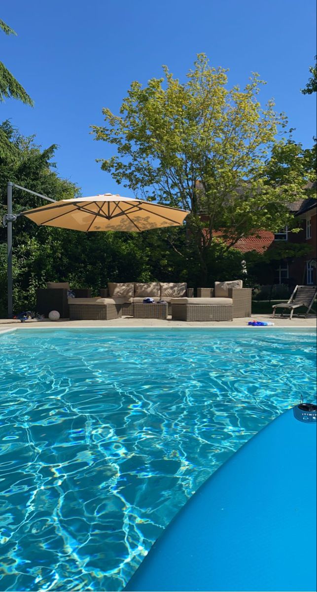 an empty swimming pool with lounge chairs and umbrella