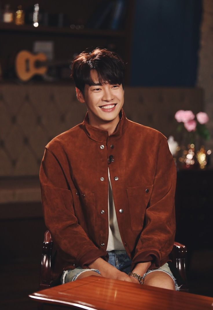 a young man sitting at a table with his hands on his knees smiling for the camera