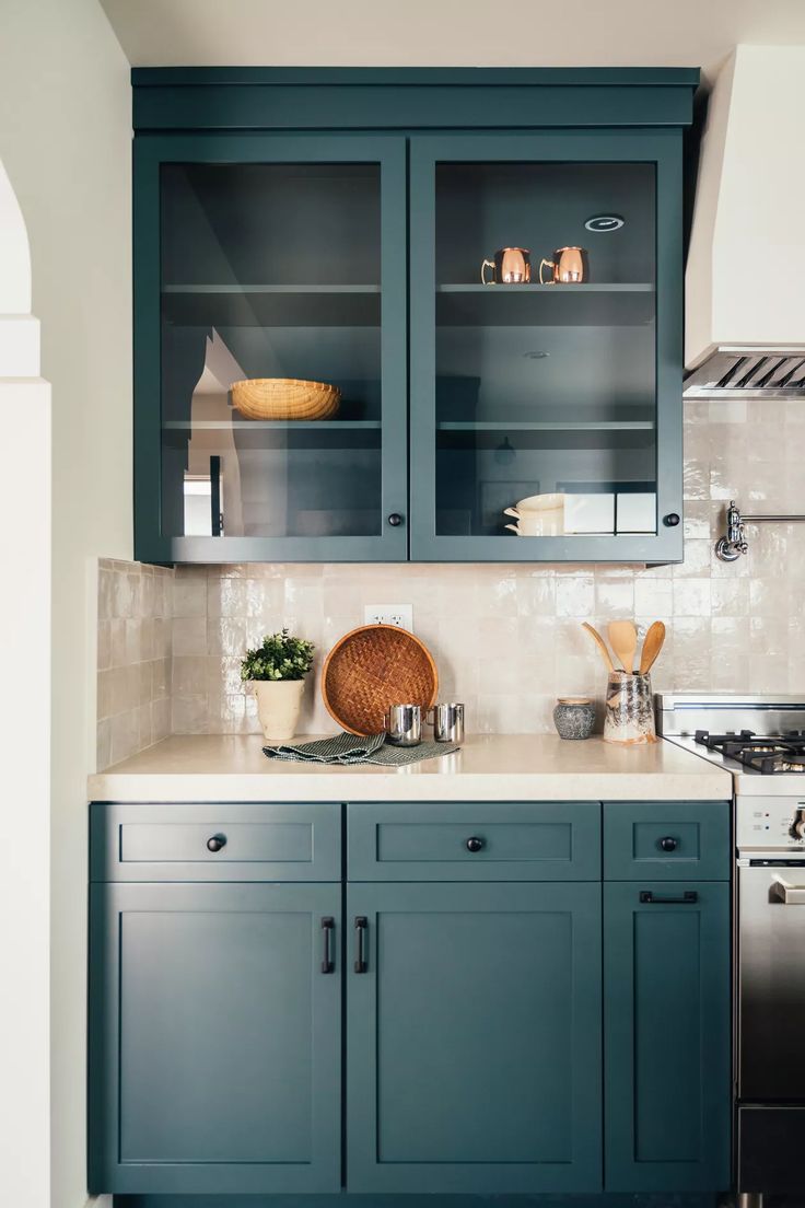 a kitchen with blue cabinets and white counter tops, along with a stove top oven