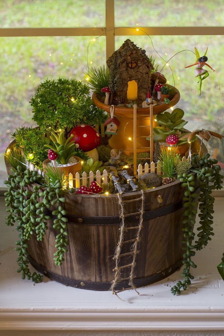 a wooden bucket filled with lots of plants and fairy figurines on top of a window sill