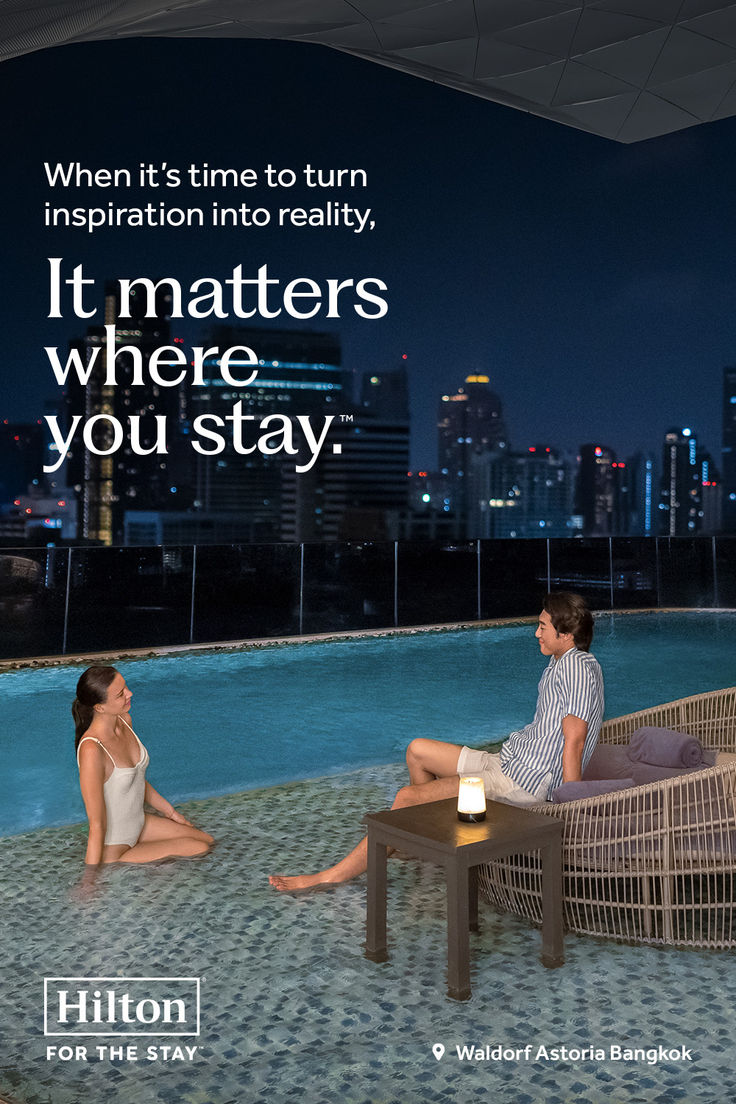 two people sitting on a bench next to a swimming pool with the words hilton written across it