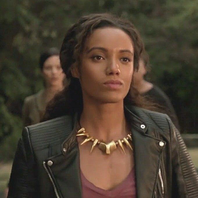 a woman wearing a leather jacket and gold statement necklace in the movie blackkkle