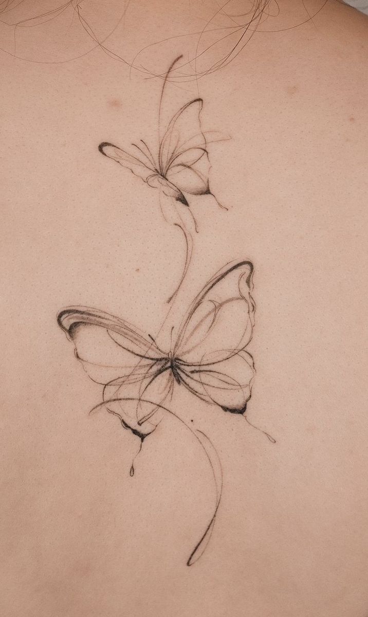 the back of a woman's shoulder with two butterflies on it