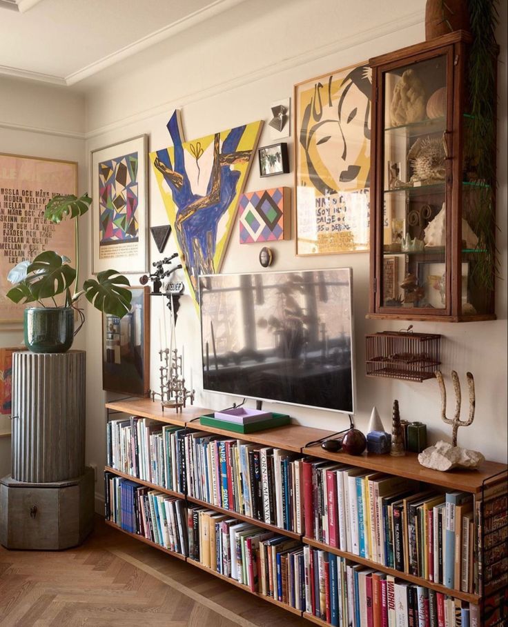 a bookshelf filled with lots of books next to a wall full of pictures