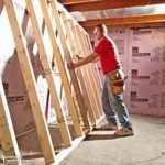 a man standing on top of a wooden floor next to a ladder in a room under construction