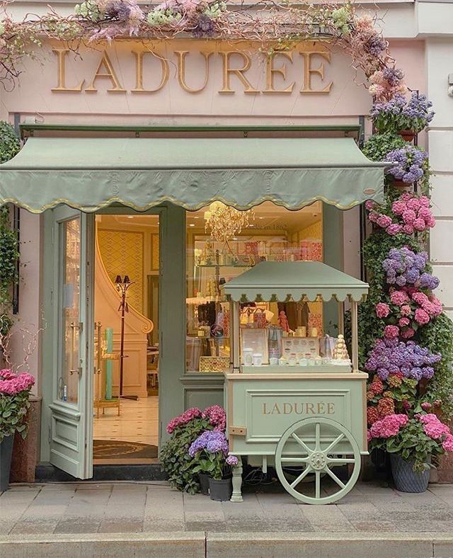 a store front with flowers on the side and a cart in front that says laduree