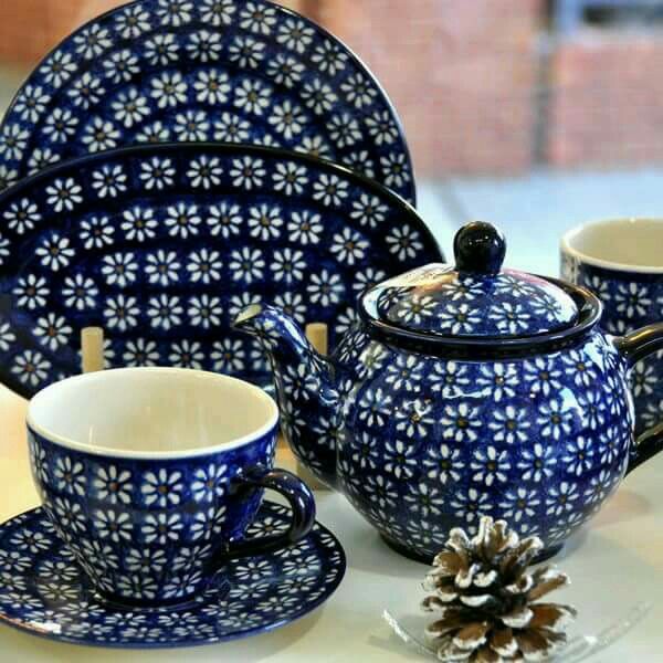 a blue tea set sitting on top of a white table next to a pine cone