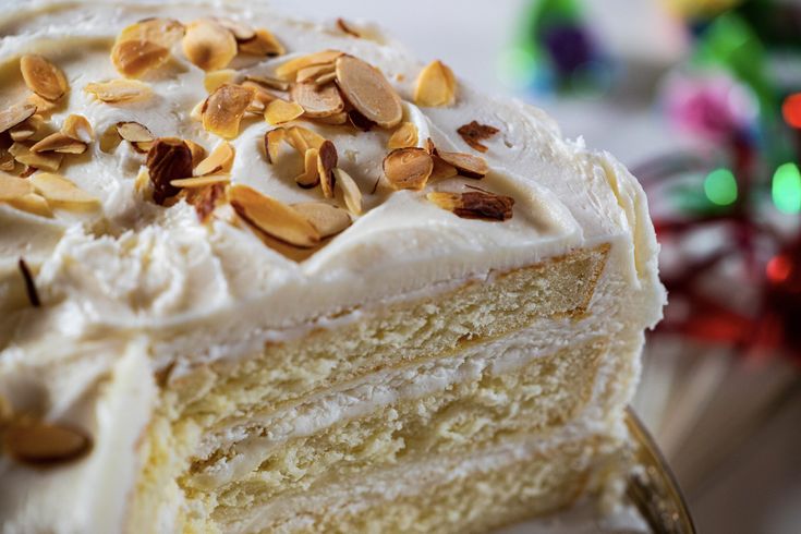 a piece of cake with white frosting and almonds on top is being held by a fork