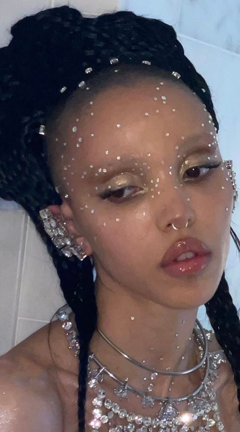 a woman with glitter on her face and necklaces around her neck in the bathtub