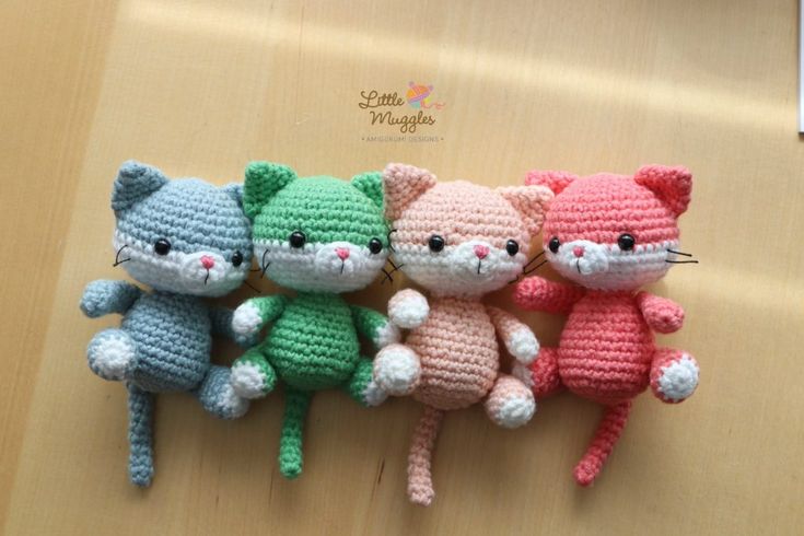 three crocheted kittens sitting next to each other on a table with one cat in the middle