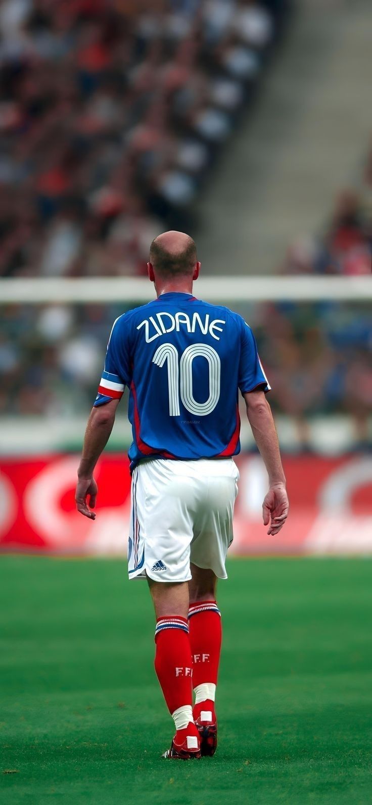 a soccer player in blue and white uniform walking on the field with his foot up