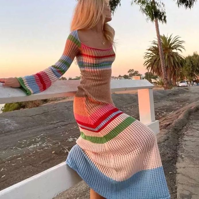 a woman in a colorful dress leaning on a rail with palm trees in the background