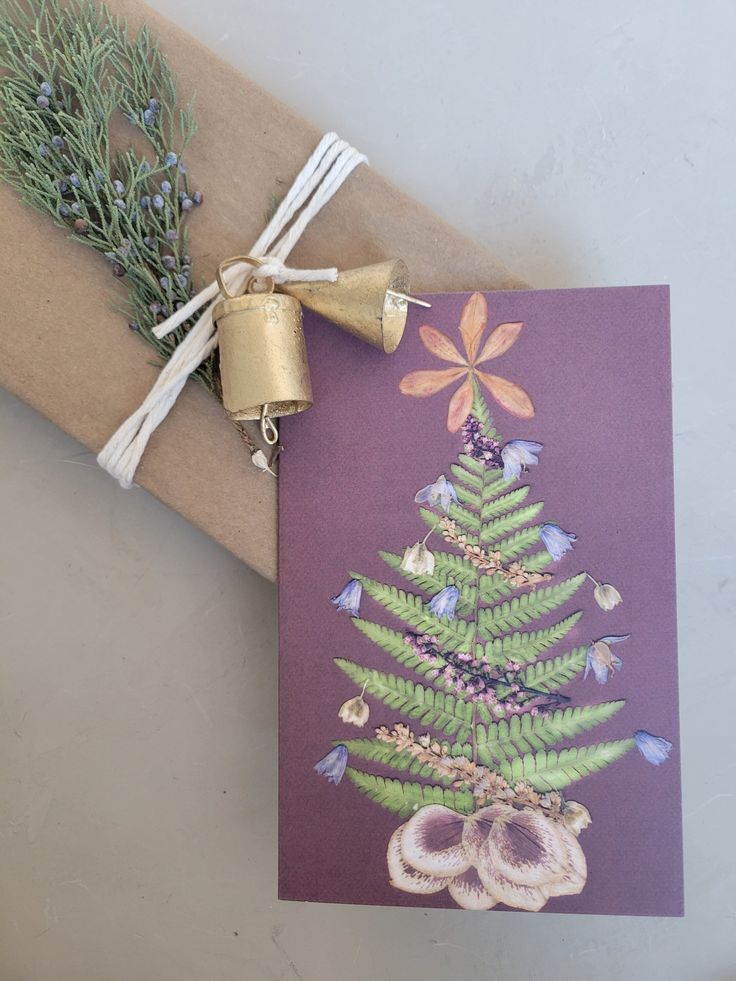 a card with a christmas tree on it next to a bell and some lavenders