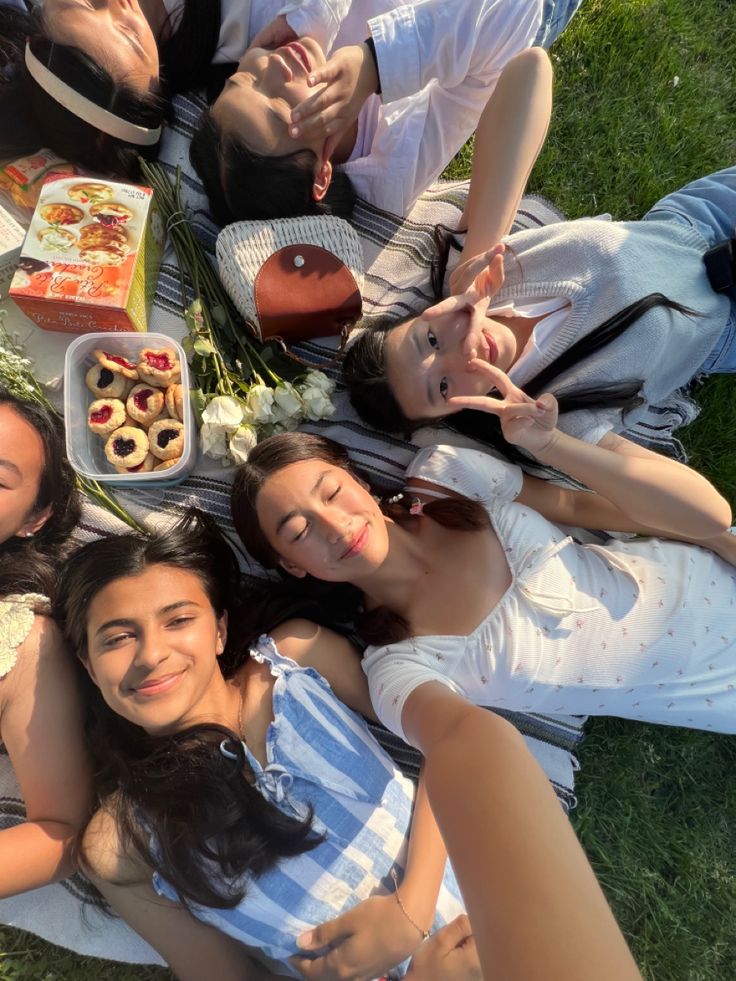 a group of people laying on top of a grass covered field next to each other