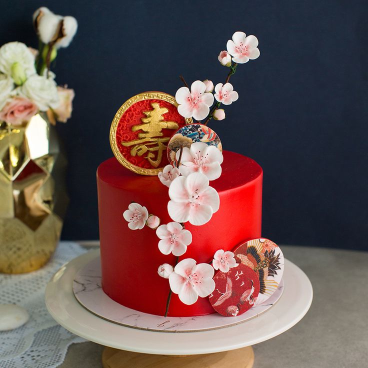 a red cake with white flowers and decorations on the top is sitting on a plate